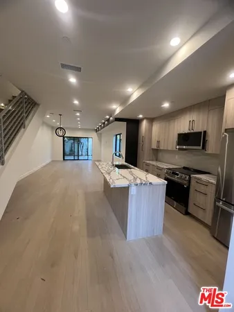 a living room with stainless steel appliances kitchen island granite countertop furniture wooden floor and view living room