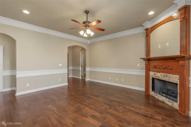 a view of an empty room with wooden floor fireplace and a window