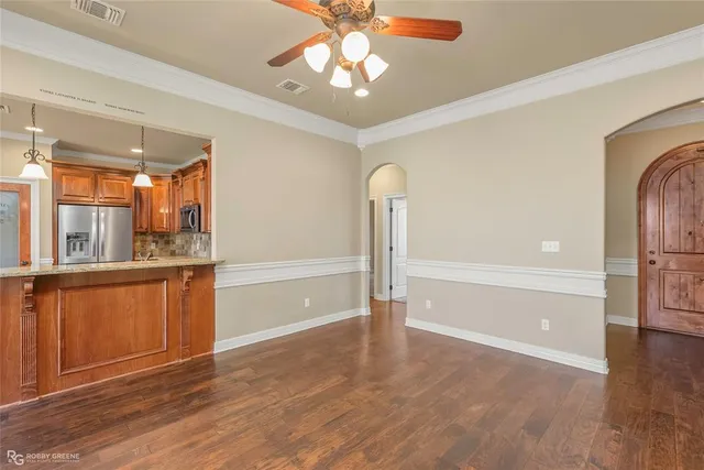 a view of an empty room with window wooden floor and a kitchen view