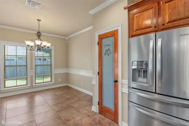 a view of a refrigerator in kitchen and an empty room