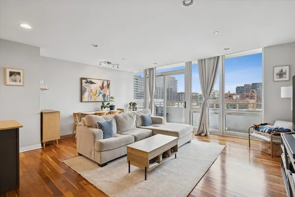 a living room with furniture a rug potted plant and a large window
