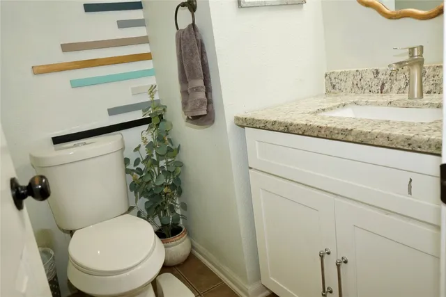 a bathroom with a granite countertop toilet and a sink