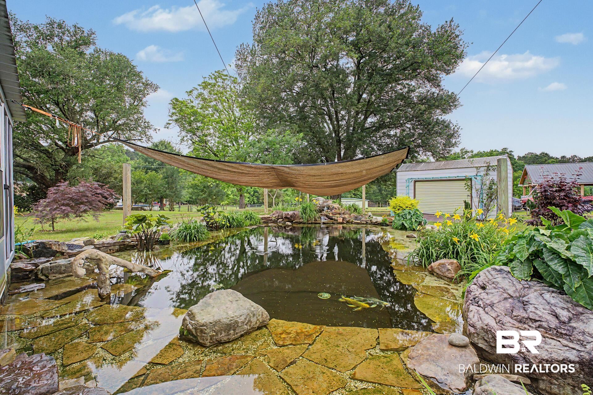 3791 Robinsonville Road Atmore, AL 36502 - Photo 19 of 47 Expansive outdoor water feature with rock-lined edges, flagstone paving, and surrounding natural landscaping