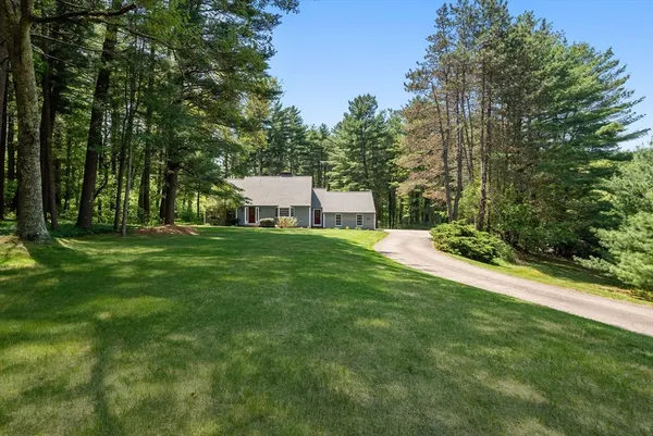 a view of a white house with a big yard and large trees