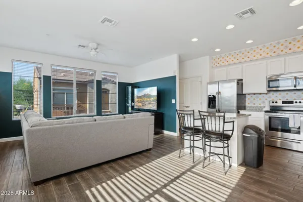 a living room with furniture a kitchen island wooden floor and stainless steel appliances
