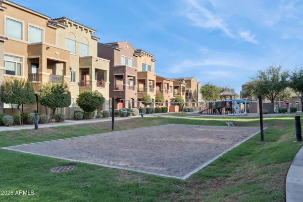 a view of a big building in front of a big yard with plants and large trees