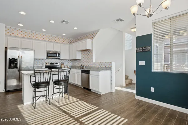 a kitchen with granite countertop a refrigerator a stove a sink a dining table and chairs with wooden floor