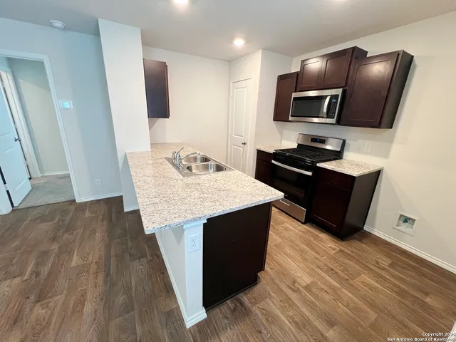 a kitchen with granite countertop stainless steel appliances sink stove microwave and cabinets