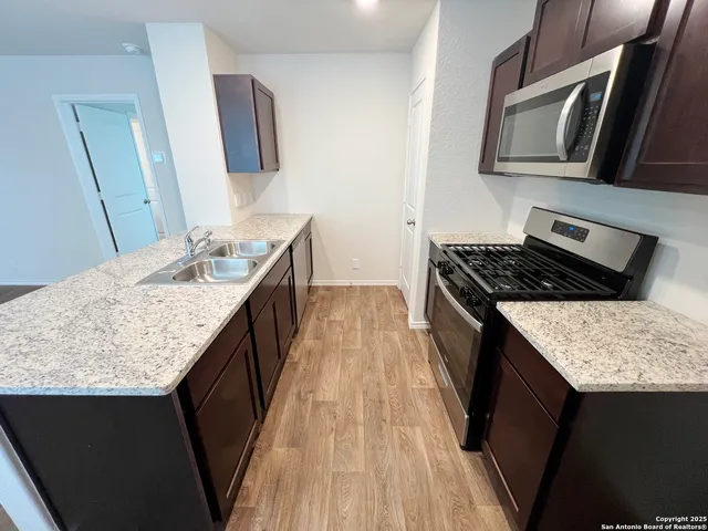 a view of kitchen island a sink wooden floor and living room