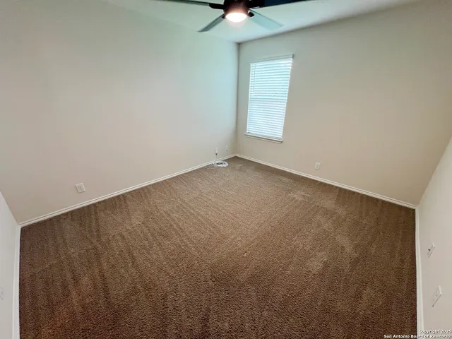 an empty room with a ceiling fan and window