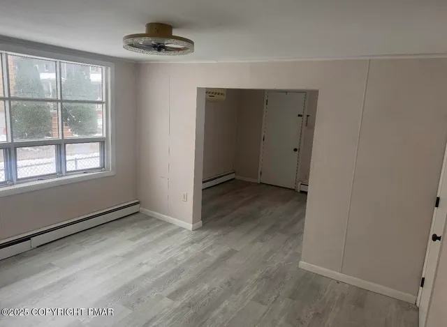 an empty room with wooden floor cabinet and windows
