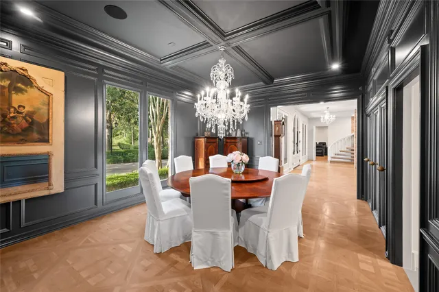 a view of a dining room with furniture a chandelier and large windows