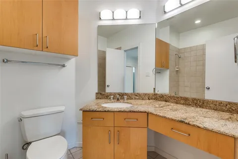 a bathroom with a granite countertop toilet sink and mirror