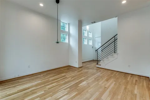 a view of an empty room with wooden floor and stairs