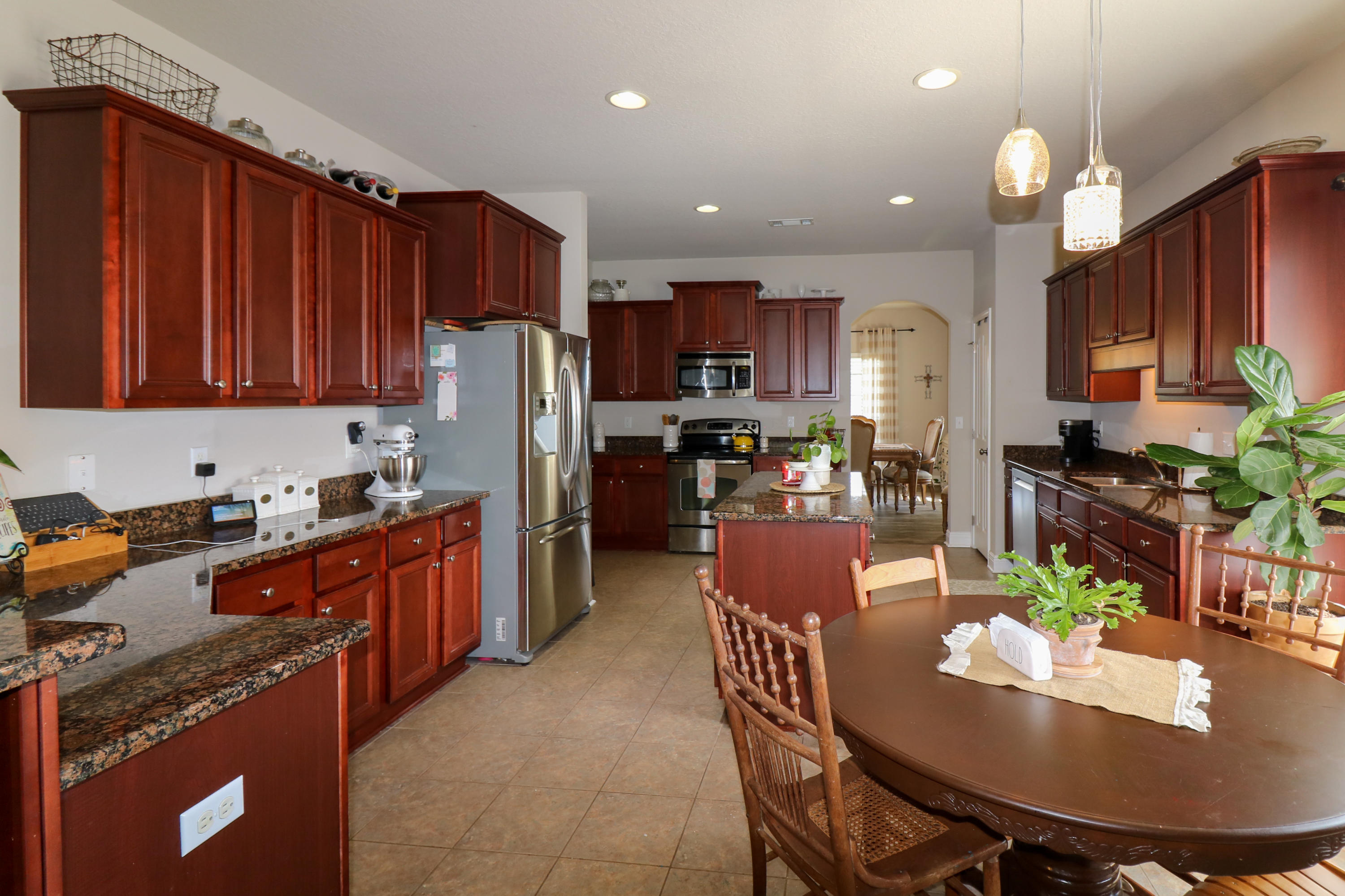 675 Red Fern Road Crestview, FL 32536 - Photo 11 of 35 a kitchen with stainless steel appliances granite countertop a refrigerator a stove a sink a dining table and chairs with wooden floor