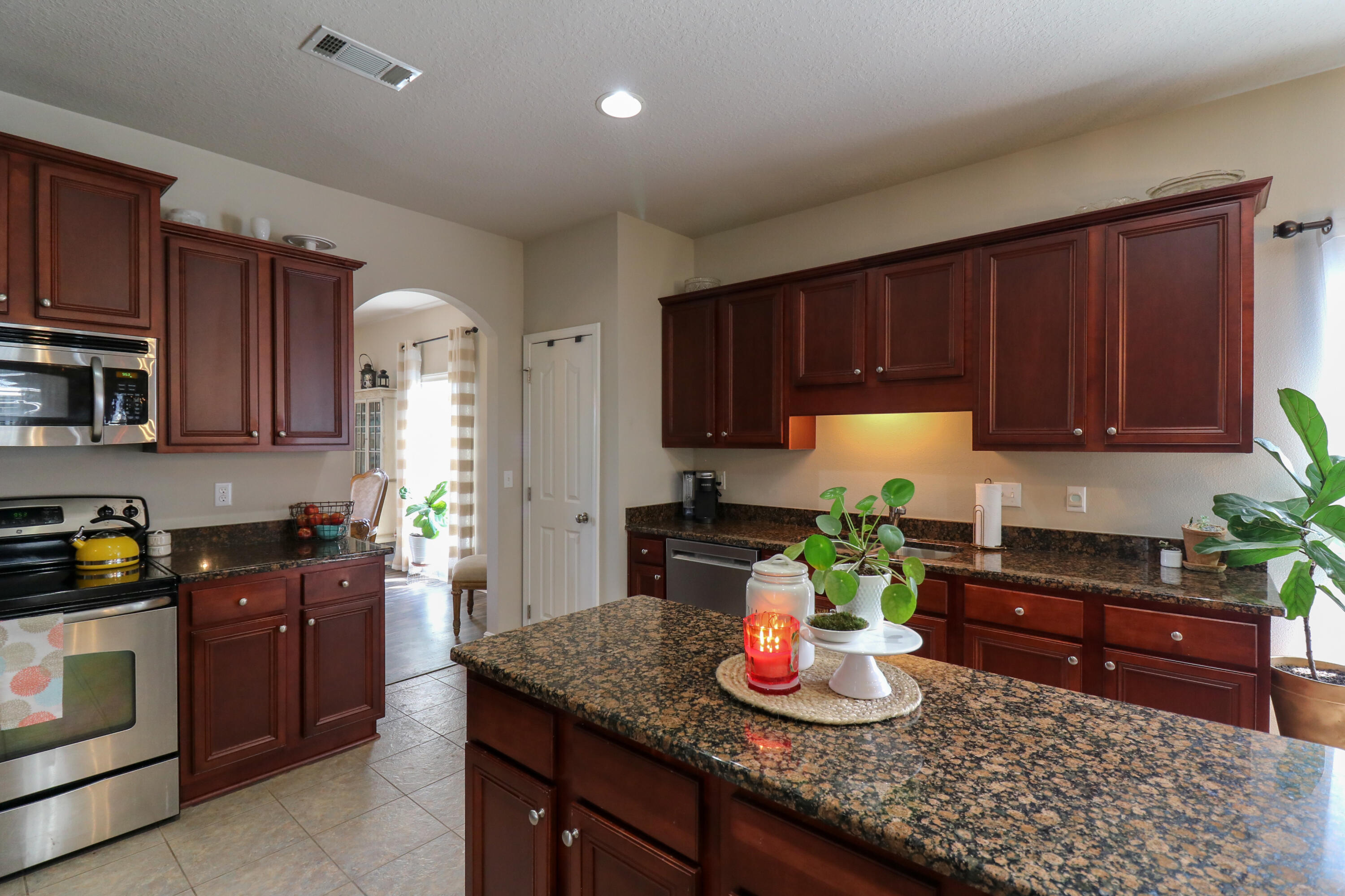 675 Red Fern Road Crestview, FL 32536 - Photo 8 of 35 a kitchen with kitchen island granite countertop wooden cabinets a stove a sink a refrigerator and blue cabinets