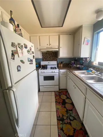a white kitchen with a stove top oven and sink