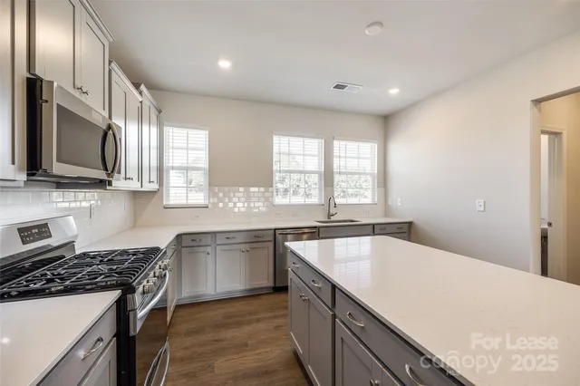 a kitchen with stainless steel appliances granite countertop a sink stove and refrigerator