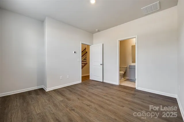 a view of an empty room with wooden floor and closet