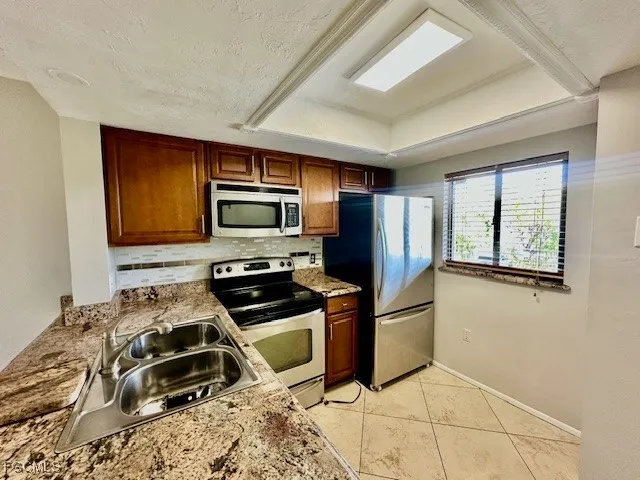 a kitchen with granite countertop a refrigerator and a stove top oven