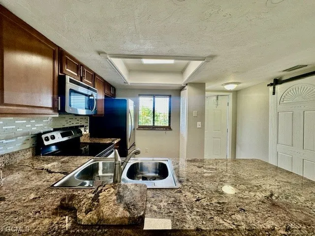 a kitchen with stainless steel appliances granite countertop a sink stove and refrigerator