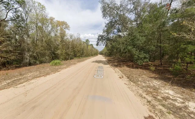 a view of a dirt road with trees in the background