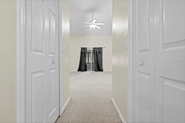 a view of a room with a ceiling fan and windows
