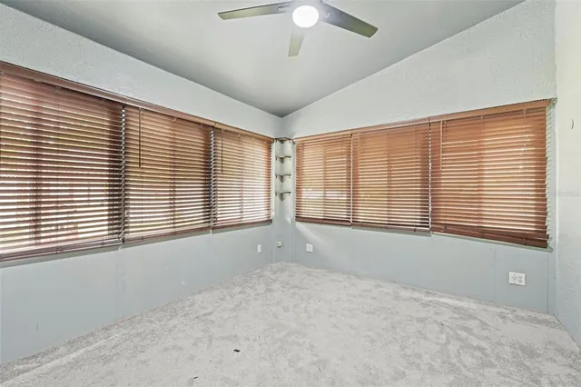 an empty room with a window and a chandelier fan