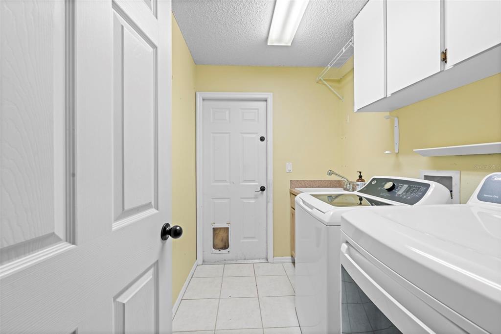 7492 Aloe Drive Spring Hill, FL 34607 - Photo 52 of 57 a utility room with a sink a cabinetry and a refrigerator