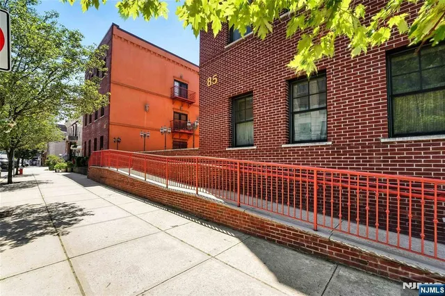 a view of a brick house with a small yard and large trees