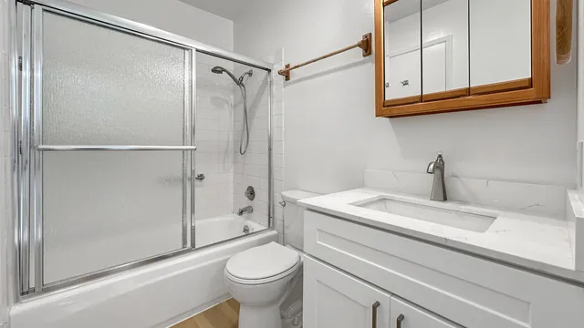 a bathroom with a granite countertop toilet sink and mirror