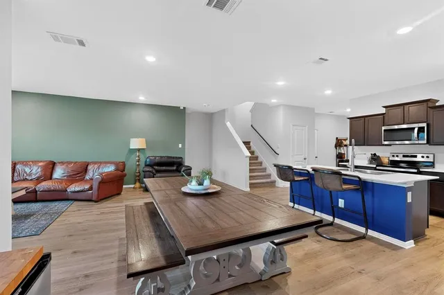 a living room with furniture kitchen view and a wooden floor