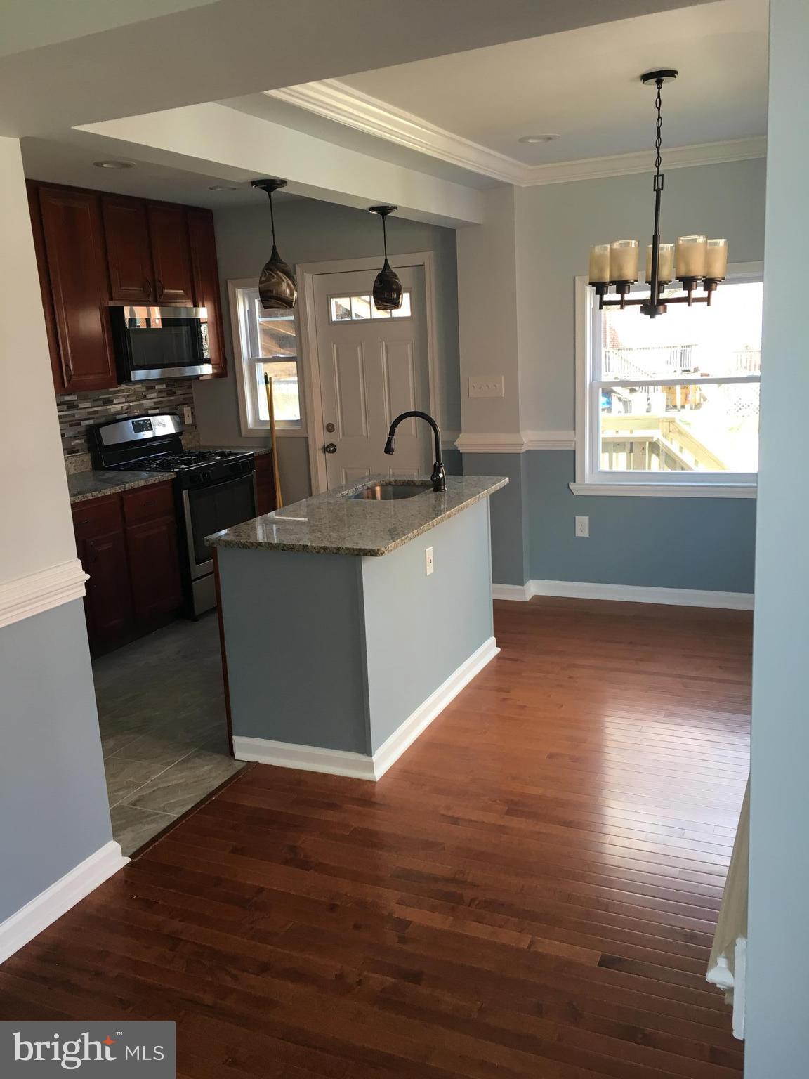 926 Arncliffe Road Baltimore, MD 21221 - Photo 5 of 24 a view of a kitchen with kitchen island a sink wooden floor and a large window