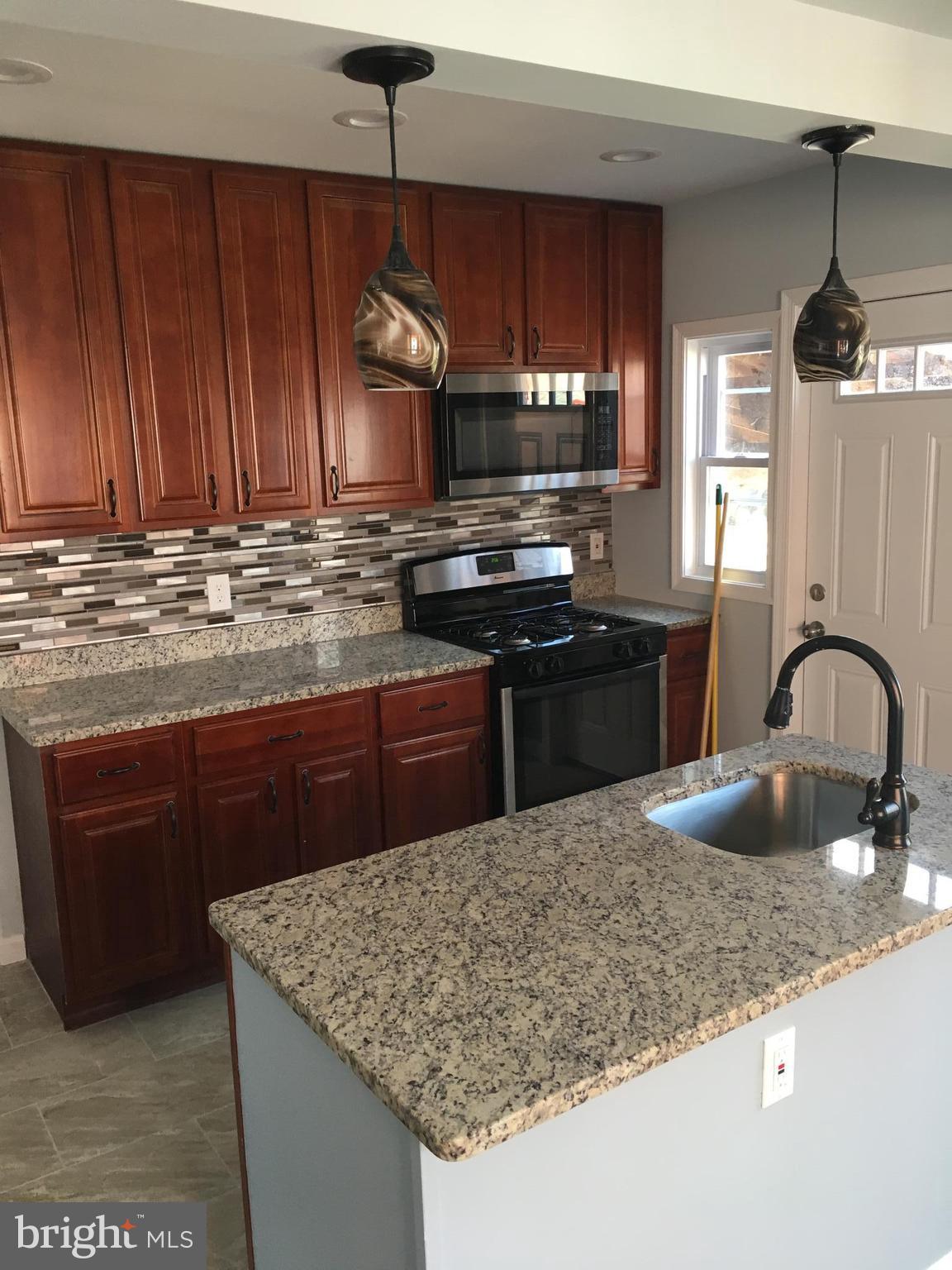 926 Arncliffe Road Baltimore, MD 21221 - Photo 7 of 24 a kitchen with kitchen island granite countertop wooden cabinets granite counter tops and a stove