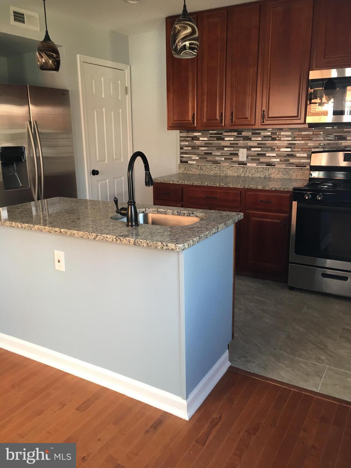 926 Arncliffe Road Baltimore, MD 21221 - Photo 8 of 24 a kitchen with stainless steel appliances granite countertop a sink a stove and wooden cabinets