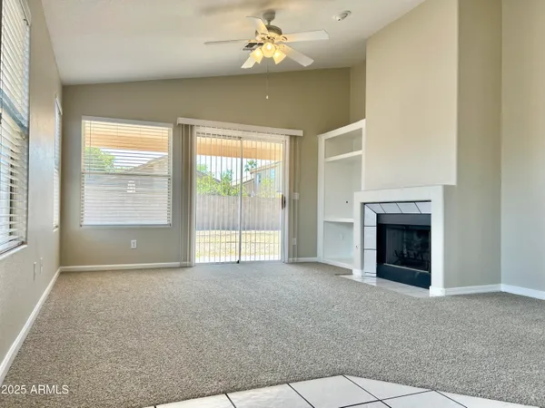 an empty room with windows and fireplace