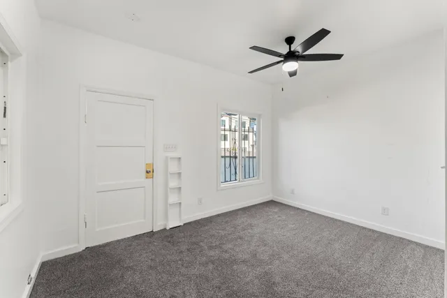 a view of a livingroom with a ceiling fan & windows