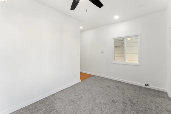 an empty room with a ceiling fan and a window