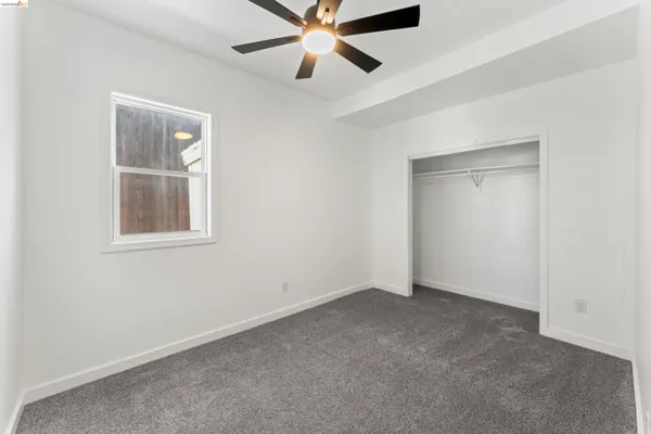 an empty room with a window and a fan