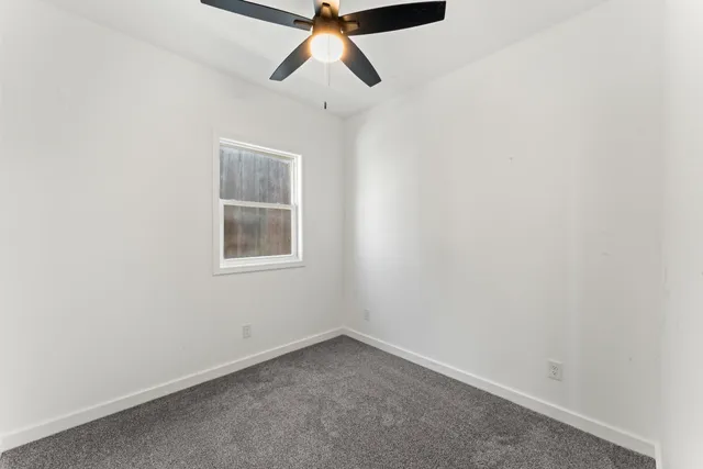 an empty room with a window and a fan