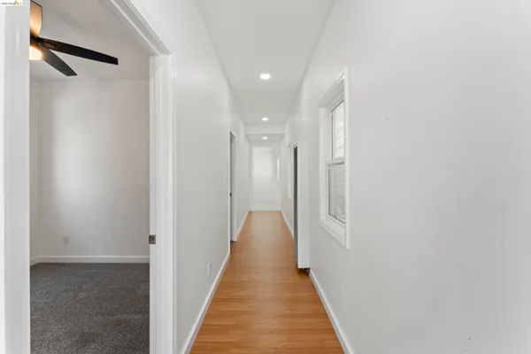 a view of a hallway with wooden floor and a bathroom