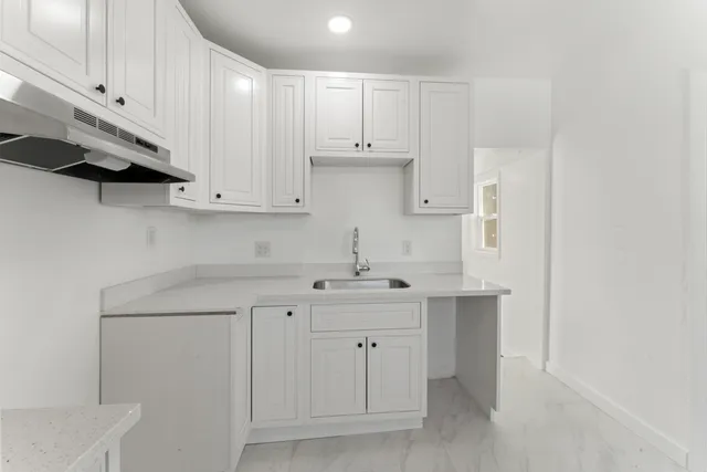 a kitchen with white cabinets and sink