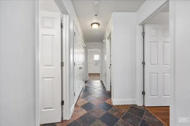 a view of a hallway with wooden floor and a bathroom