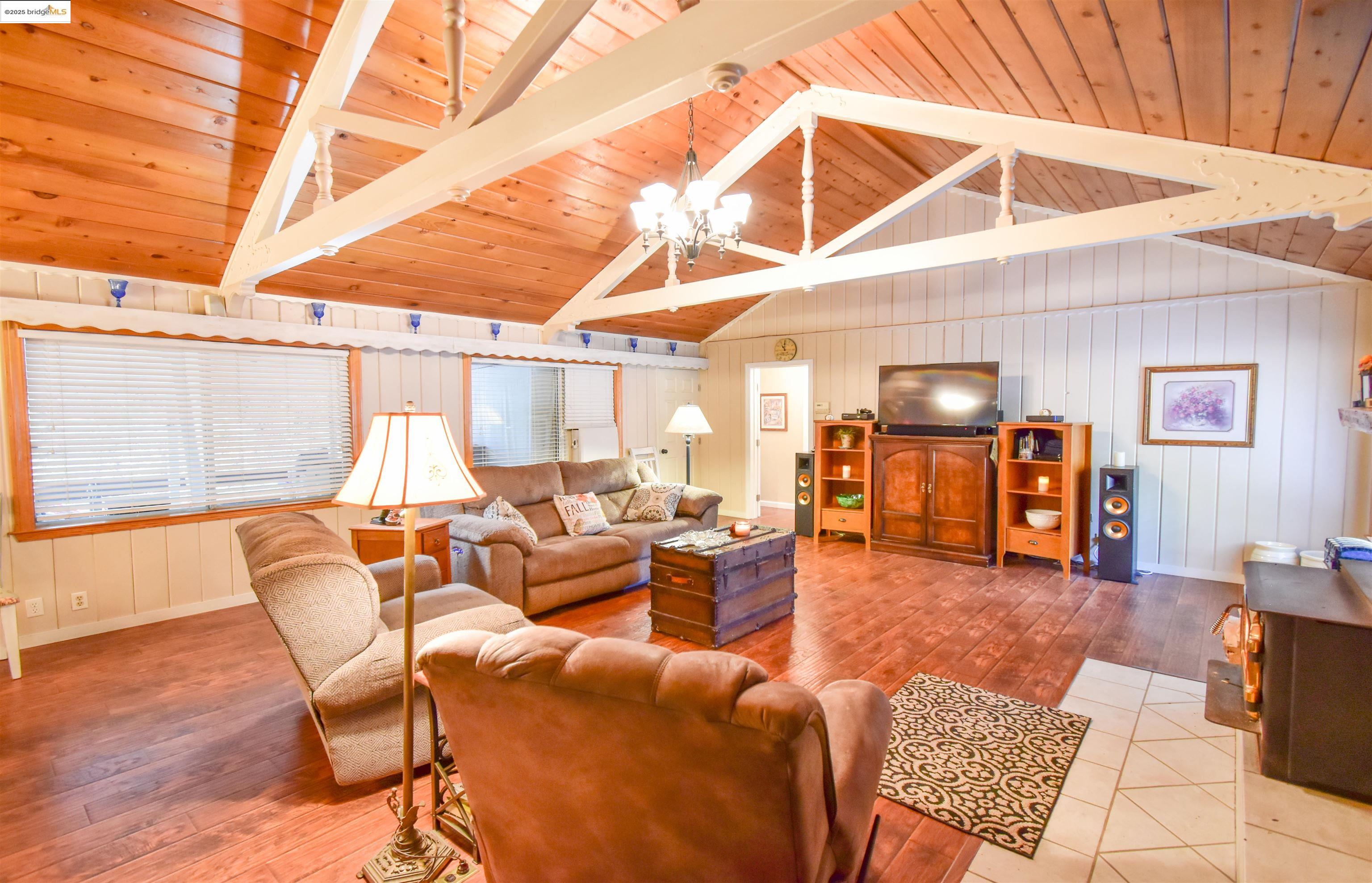 20705 Muheli Road Mi Wuk Village, CA 95346 - Photo 2 of 18 Living room featuring upgraded flooring and open beam, knotty pine celiling, wood stove insert with tile hearth