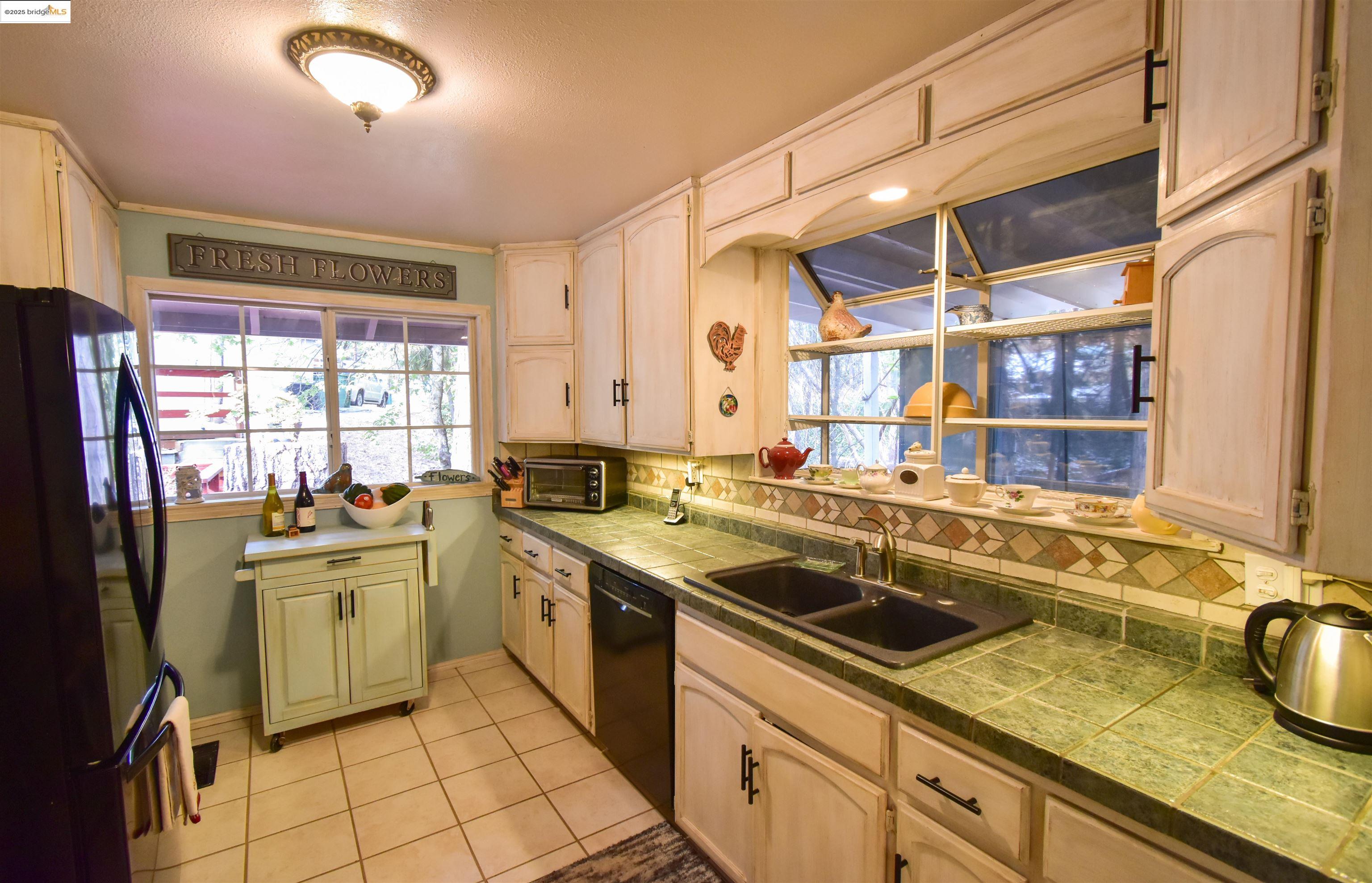20705 Muheli Road Mi Wuk Village, CA 95346 - Photo 5 of 18 Updated kitchen with farm style cabinets, tile flooring, tile counters and decorative backsplash, garden window and healthy amount of natural light
