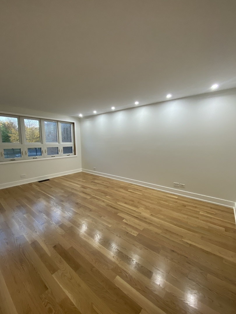 3270 North Elston Avenue, Unit 1 Chicago, IL 60618 - Photo 2 of 13 an empty room with wooden floor and windows