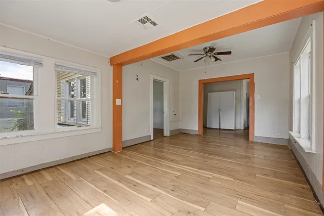 a view of an empty room with wooden floor and a window