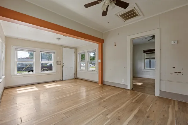a view of an empty room with wooden floor and a window