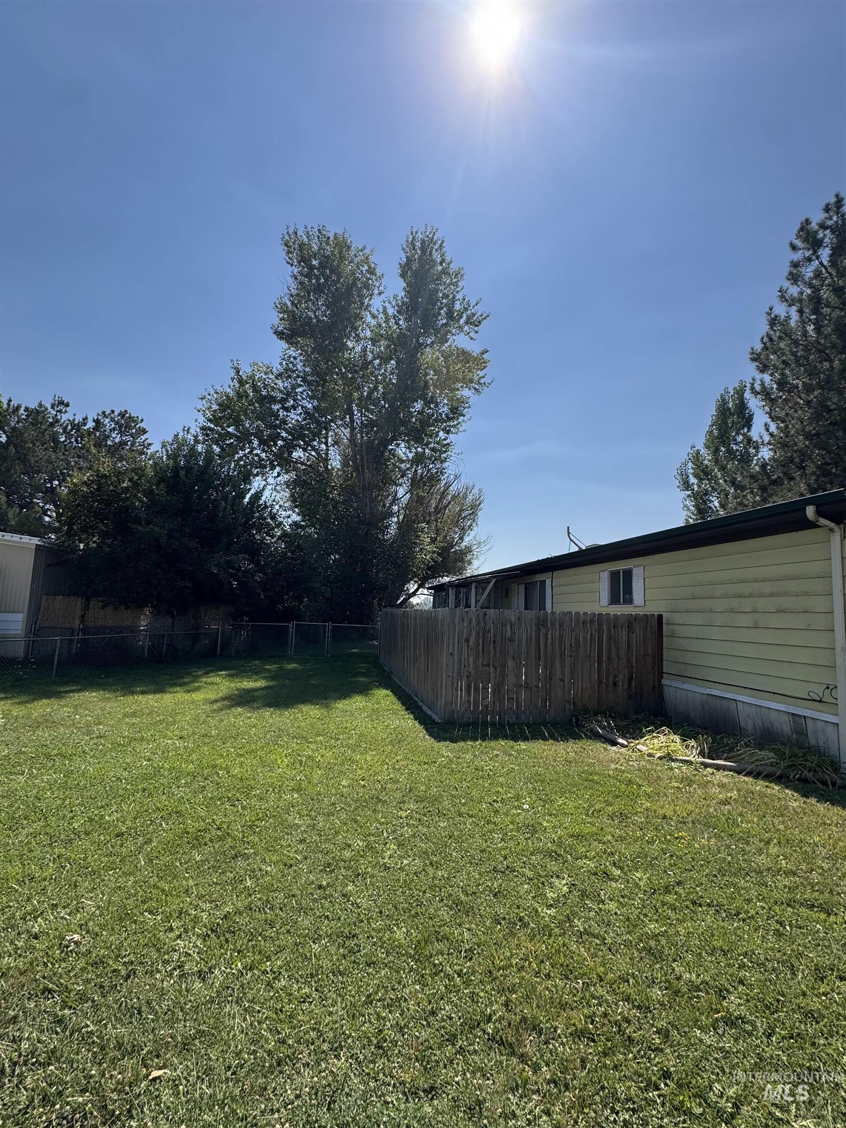1200 Artesian Road, Unit 36 Eagle, ID 83616 - Photo 13 of 13 Expansive green lawn with a wood plank fence and mature trees