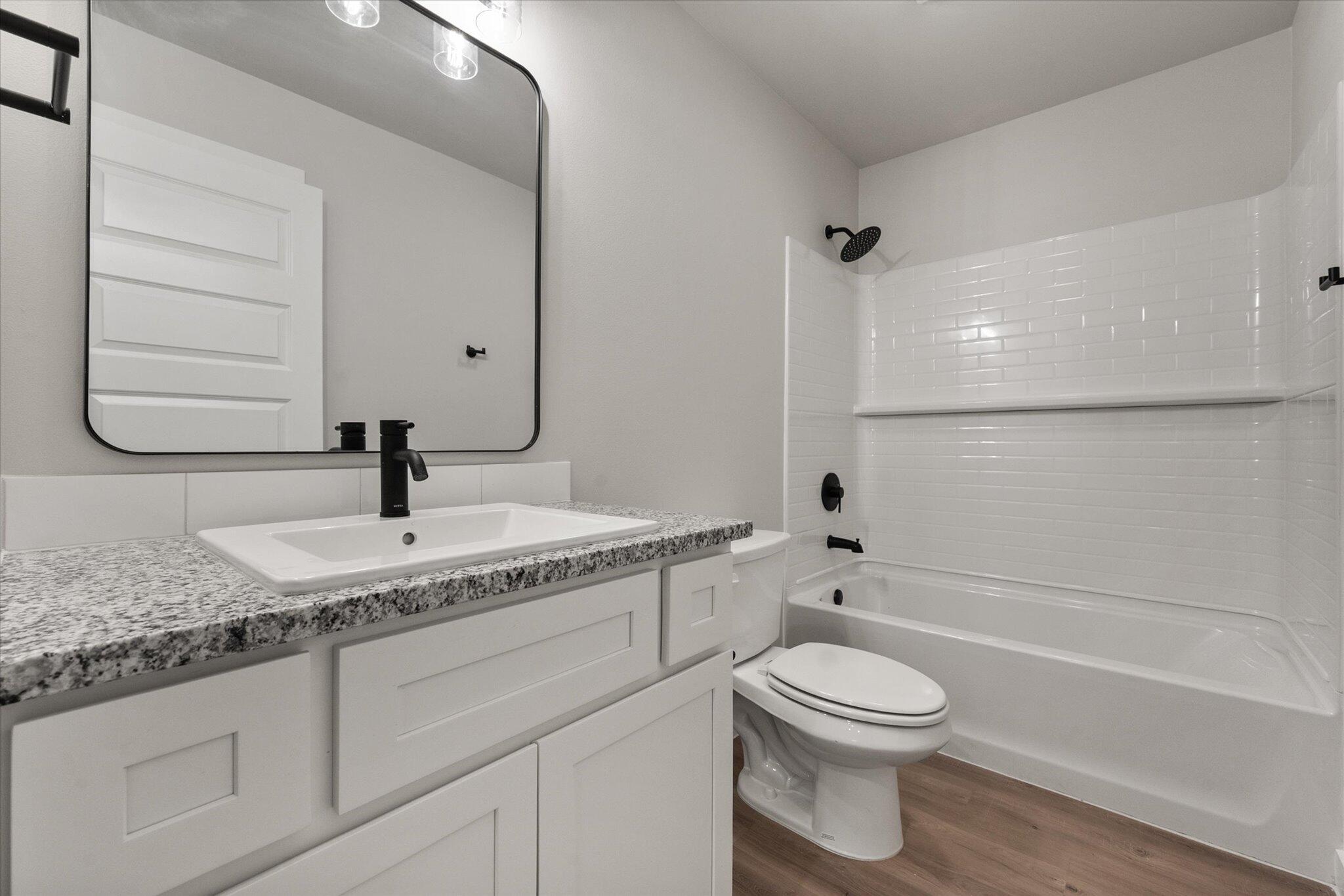 2332 136th Street Lubbock, TX 79423 - Photo 17 of 19 a bathroom with a granite countertop toilet a sink and a bathtub